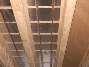 Photo showing the aluminum heat transfer plates installed in continuous coverage for a radiant floor heating system.